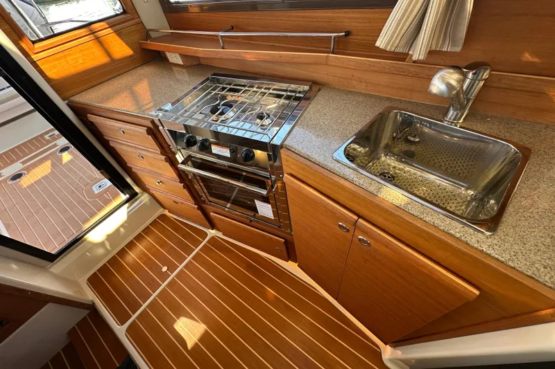 Two For The Road II Yacht Photos Pics 2020 Ranger Tugs R-29 galley with stove, sink, and wood cabinetry.