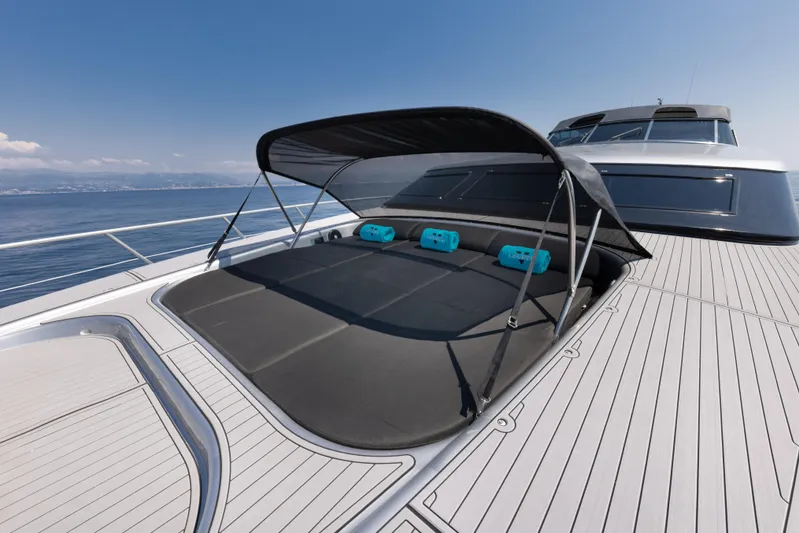 Lauren V Yacht Photos Pics Luxurious 1997 Mangusta 103 yacht deck with sunshade and cushions, set against a serene ocean backdrop.