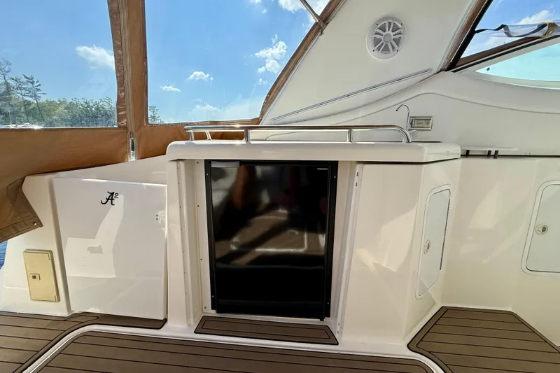  Yacht Photos Pics 2004 Cruisers Yachts 3672 cockpit with fridge, teak flooring, and sunny sky view.