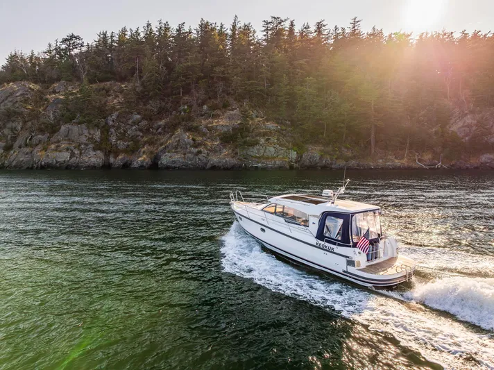 Keokuk Yacht Photos Pics Nimbus 365 Coupe 2020 cruising near a forested shoreline at sunset.