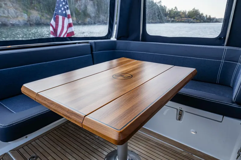 Keokuk Yacht Photos Pics Interior of 2020 Nimbus 365 Coupe with wooden table and seating, American flag visible.