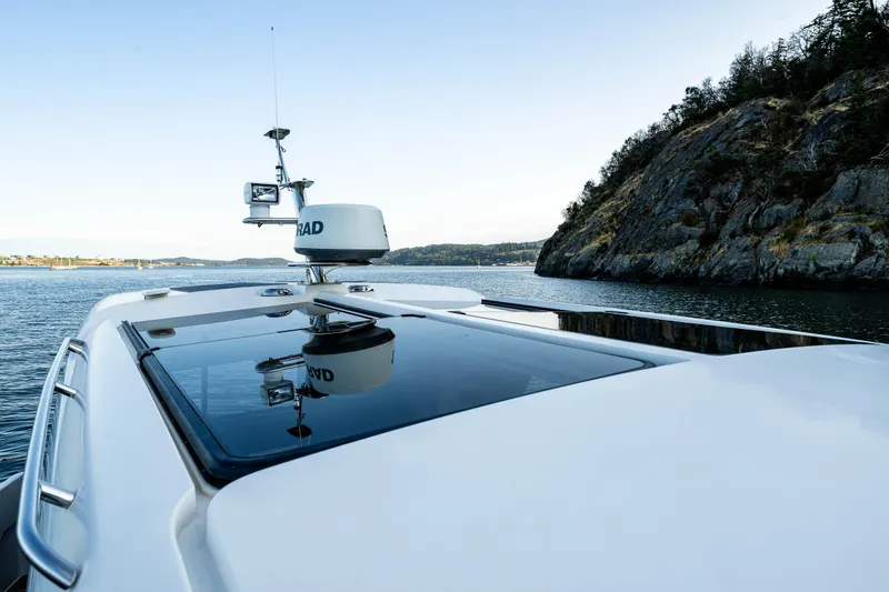 Keokuk Yacht Photos Pics Nimbus 365 Coupe 2020 cruising near rocky shoreline, featuring sleek design and advanced navigation equipment.