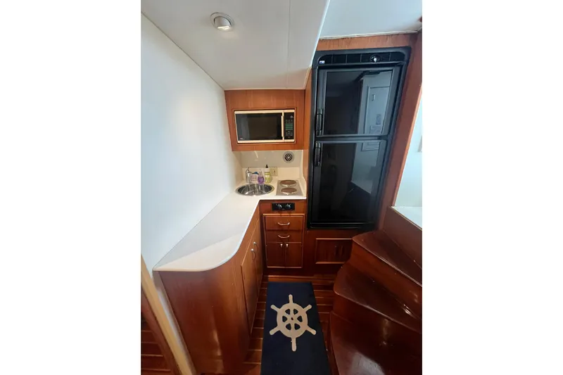  Yacht Photos Pics 1993 Buddy Davis 38 Express yacht interior with kitchenette, featuring microwave, sink, and wooden cabinetry.