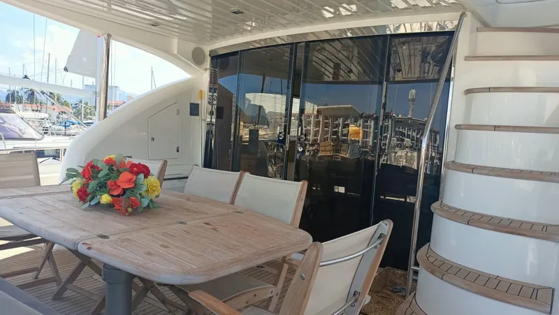 La Chaparrita Yacht Photos Pics Outdoor dining area on a 2011 Sunseeker Manhattan 70 yacht with wooden table and chairs.