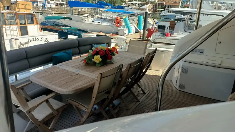 La Chaparrita Yacht Photos Pics Sunseeker Manhattan 70 yacht 2011, outdoor dining area with wooden table and chairs, marina background.