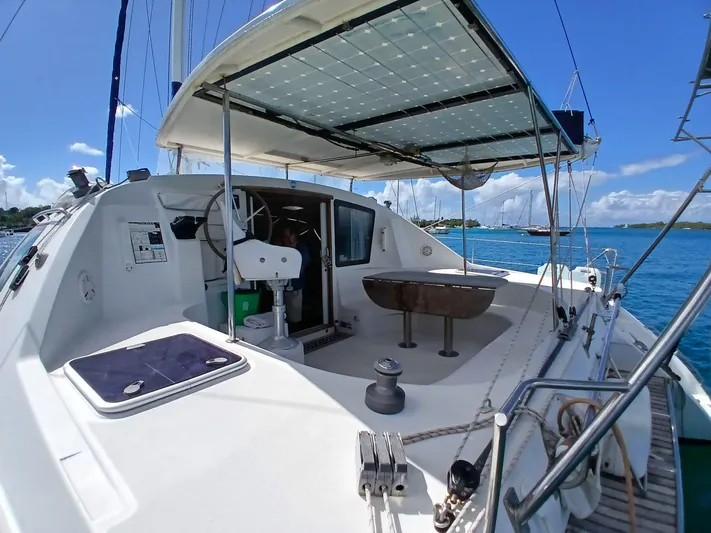 Osina Yacht Photos Pics Catamaran Privilege 37, 2000 model, with spacious deck and solar panels, anchored in clear blue waters.