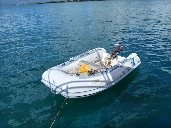 Osina Yacht Photos Pics Small inflatable boat with outboard motor floating on calm blue water.