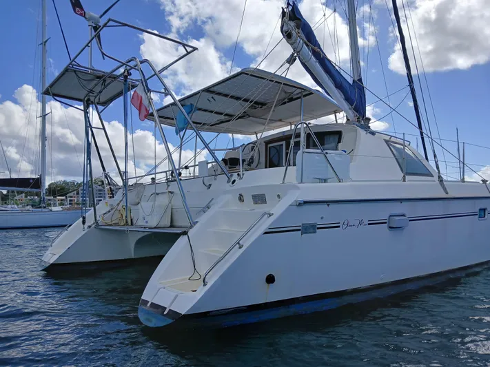 Osina Yacht Photos Pics Catamaran Privilege 37, 2000 model, anchored on water under a partly cloudy sky.