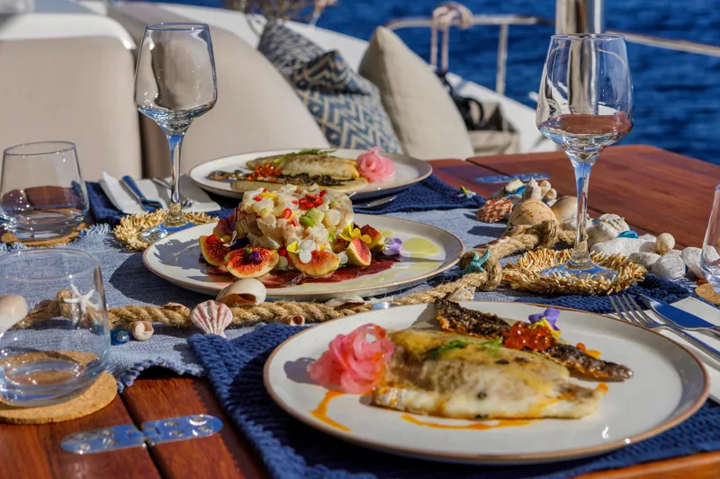  Yacht Photos Pics Luxurious dining setup on Lagoon 55 yacht, featuring gourmet dishes and elegant tableware.