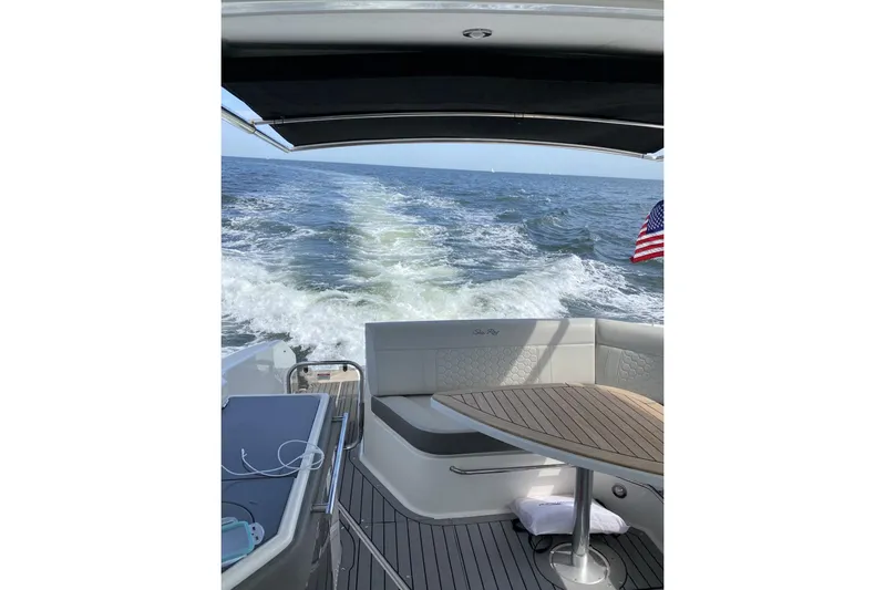  Yacht Photos Pics 2020 Sea Ray Sundancer 320 cruising on open water, rear view with American flag.