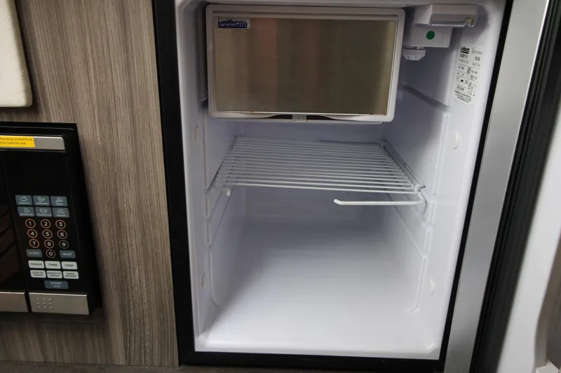  Yacht Photos Pics Empty refrigerator inside 2020 Sea Ray Sundancer 320 yacht, with adjacent control panel.