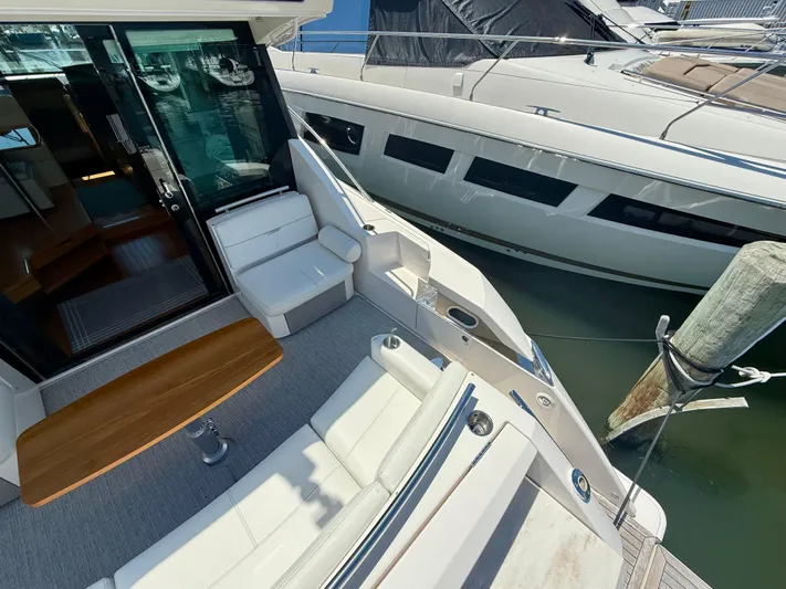  Yacht Photos Pics 2017 Tiara Yachts C44 Coupe deck with seating and table, docked beside another yacht.