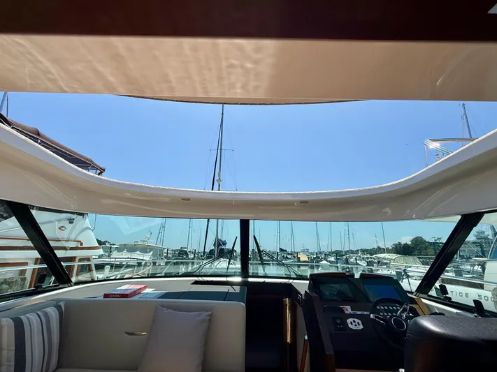  Yacht Photos Pics Interior view of 2017 Tiara Yachts C44 Coupe, showcasing helm and marina backdrop.