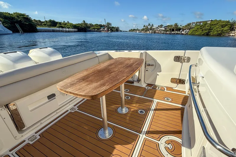  Yacht Photos Pics 2017 Boston Whaler 370 Outrage boat deck with wooden table, scenic waterfront view.