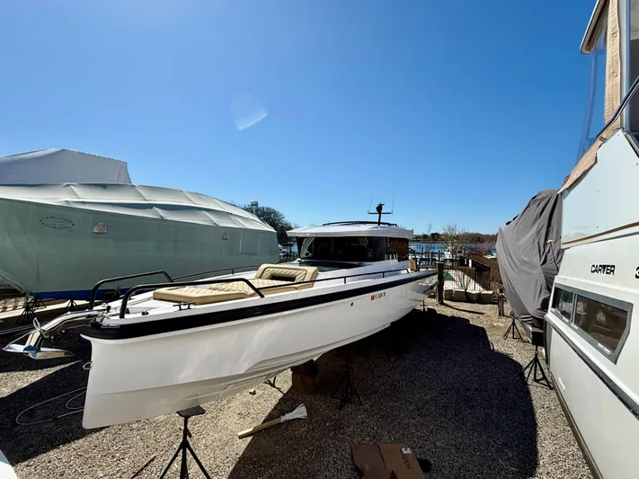 Yacht Photos Pics 2021 Axopar 37 boat on stands, surrounded by other covered boats in a sunny marina.