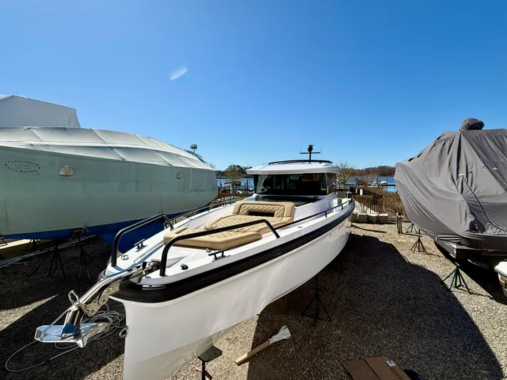  Yacht Photos Pics 2021 Axopar 37 boat on display, surrounded by covered vessels, under clear blue sky.
