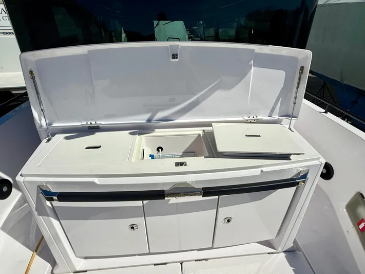  Yacht Photos Pics 2021 Axopar 37 boat with open storage compartment and sink on deck.