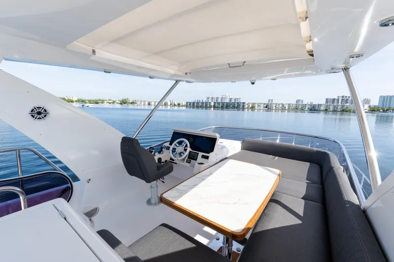 Andromeda Yacht Photos Pics 2023 Azimut Fly 50 yacht flybridge with seating, table, and helm overlooking water.