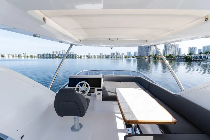 Andromeda Yacht Photos Pics 2023 Azimut Fly 50 yacht interior with steering wheel and seating area, overlooking waterfront cityscape.