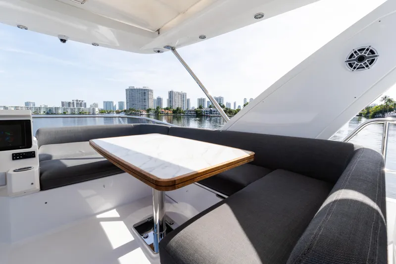 Andromeda Yacht Photos Pics 2023 Azimut Fly 50 yacht interior with elegant seating and table, overlooking city skyline.