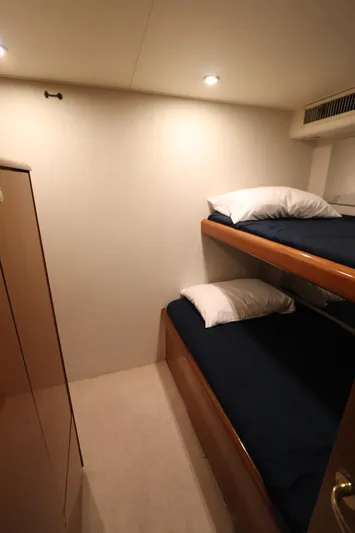 Angie Yacht Photos Pics Bunk beds in a 2000 Viking 65 yacht cabin, featuring cozy bedding and warm lighting.