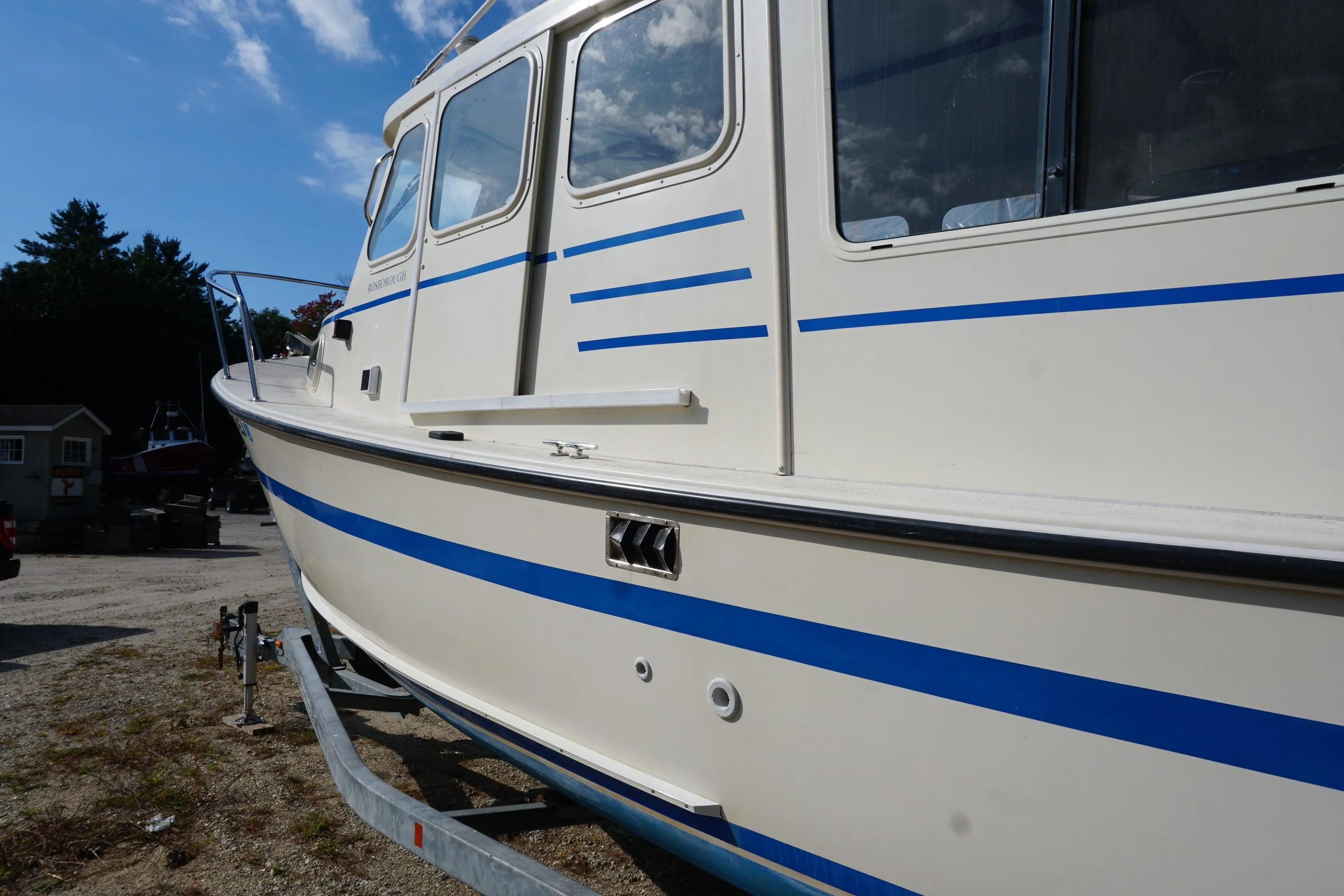 2002 Rosborough RF-246 Sedan Cruiser with blue stripes on a trailer, side view.