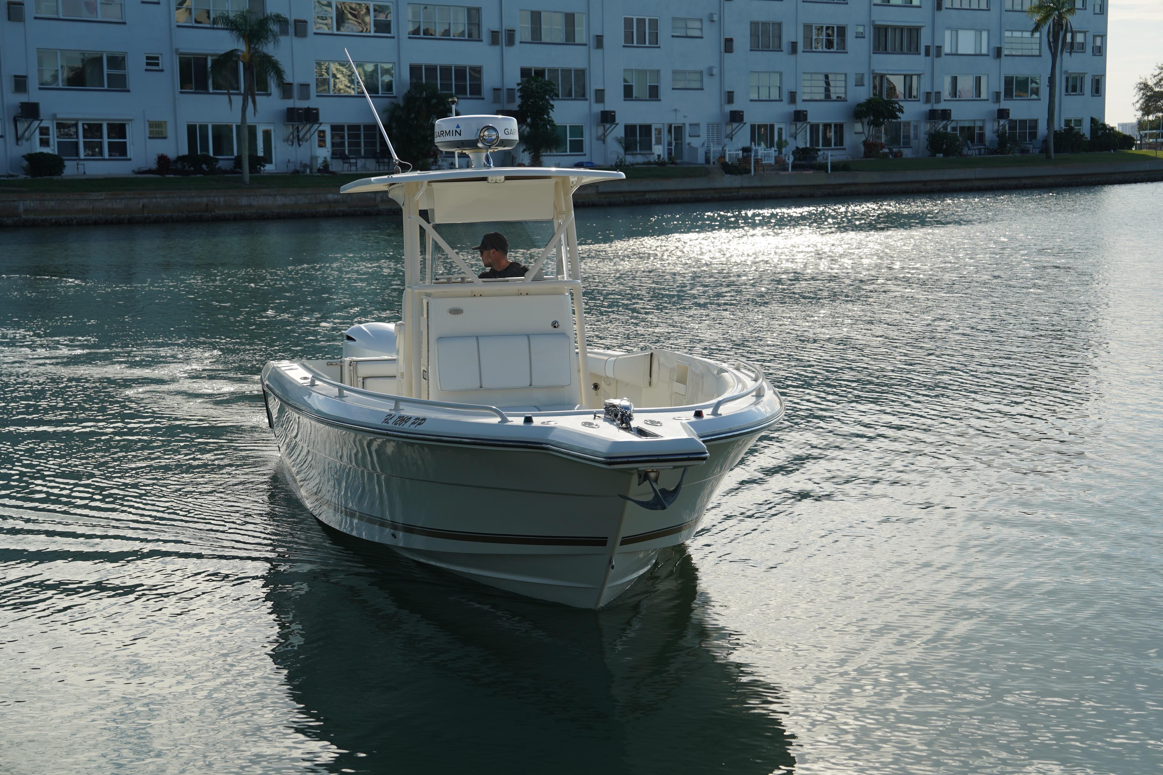 2013 Stamas 317 Tarpon boat cruising near waterfront buildings.