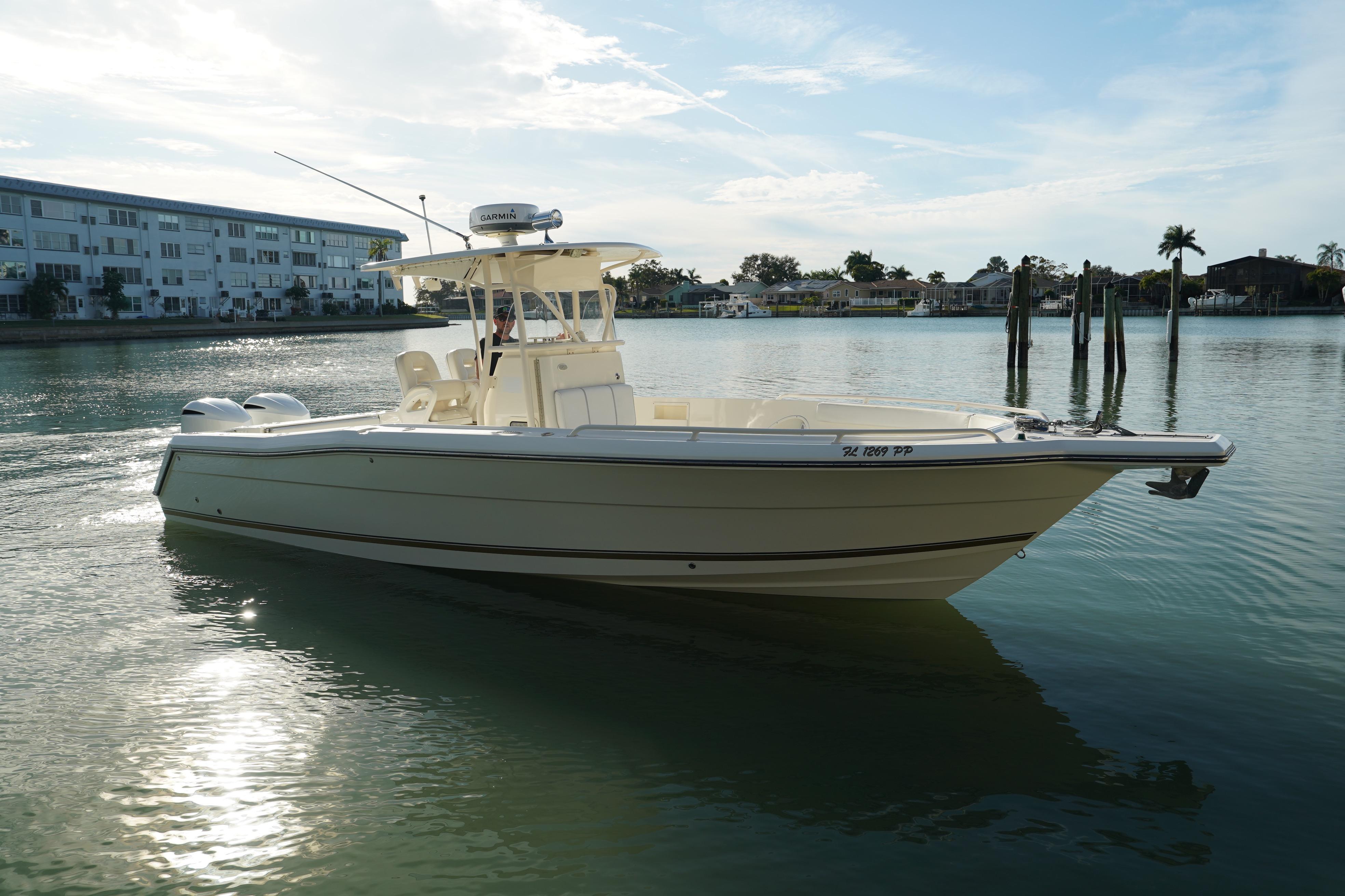 2013 Stamas 317 Tarpon boat on calm water, with a scenic waterfront backdrop.