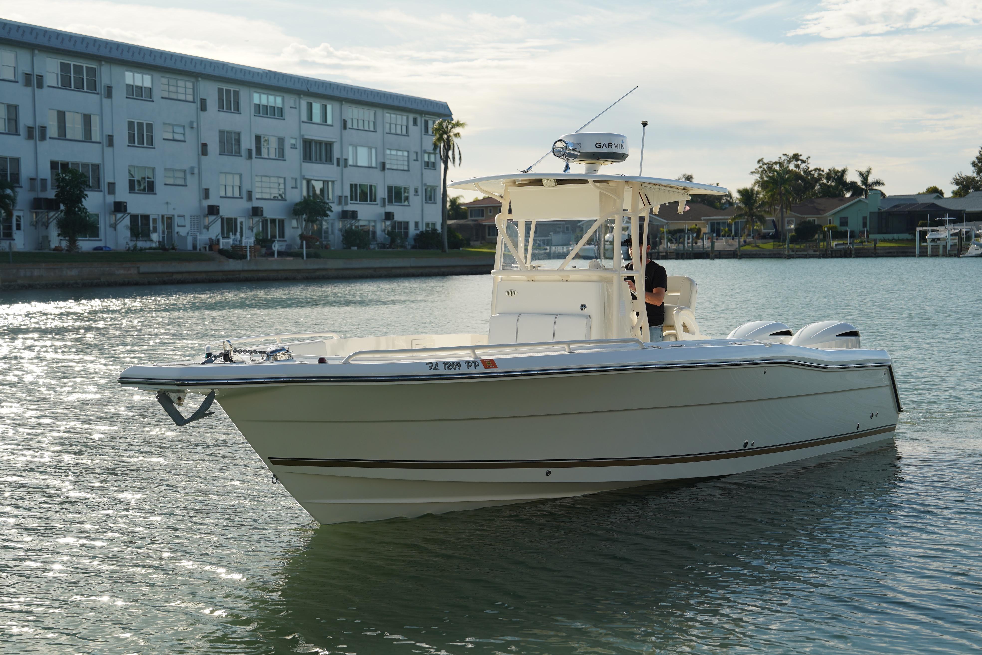 2013 Stamas 317 Tarpon boat on calm water near waterfront buildings.