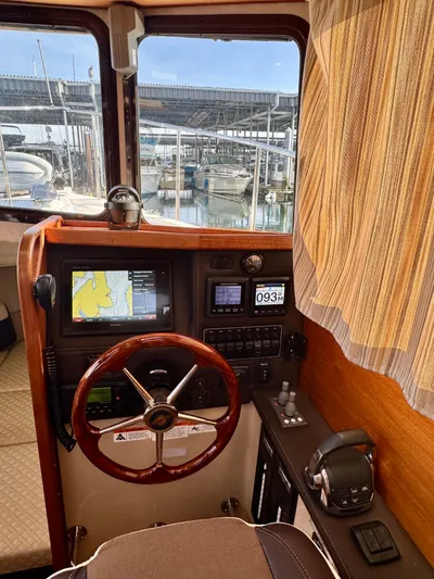 Lone Ranger Yacht Photos Pics 2017 Ranger Tugs Sedan helm with navigation system, wooden steering wheel, and marina view.
