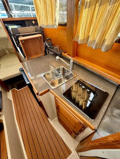 Lone Ranger Yacht Photos Pics 2017 Ranger Tugs Sedan interior kitchen with sink, stove, and wooden cabinetry.