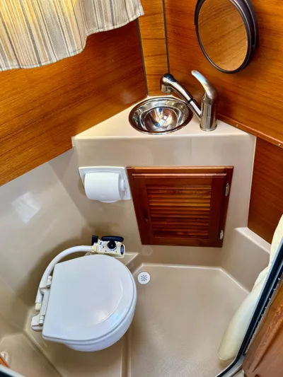 Lone Ranger Yacht Photos Pics 2017 Ranger Tugs Sedan bathroom with compact toilet, sink, and wooden accents.