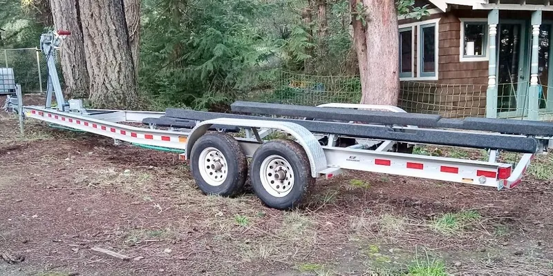 Lone Ranger Yacht Photos Pics Trailer for 2017 Ranger Tugs Sedan, parked outdoors near trees and a wooden building.