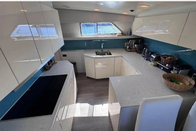 Blue Moon Yacht Photos Pics Modern kitchen interior on 2000 Sanlorenzo SL88 yacht, featuring sleek white cabinetry and blue accents.