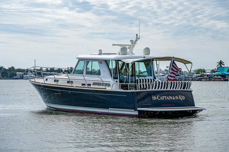 Captain And The Kid Yacht Photos Pics 2012 Sabre 48 Salon Express yacht on calm water, American flag displayed.