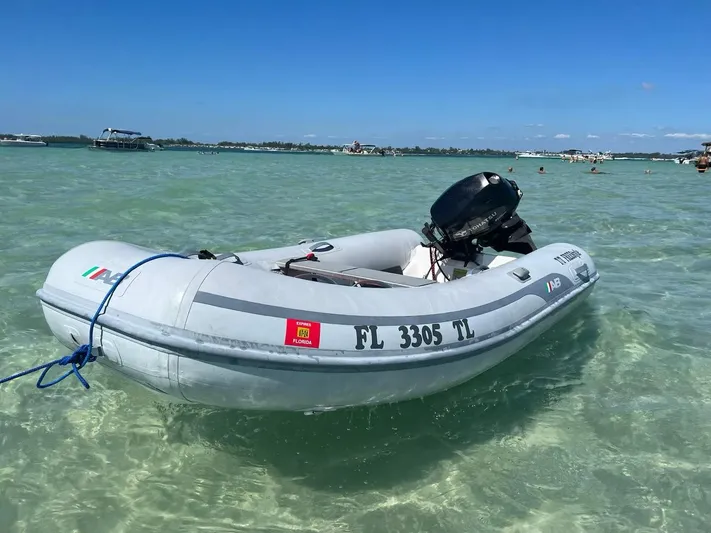  Yacht Photos Pics Inflatable boat anchored in clear water, sunny day, distant yachts visible.