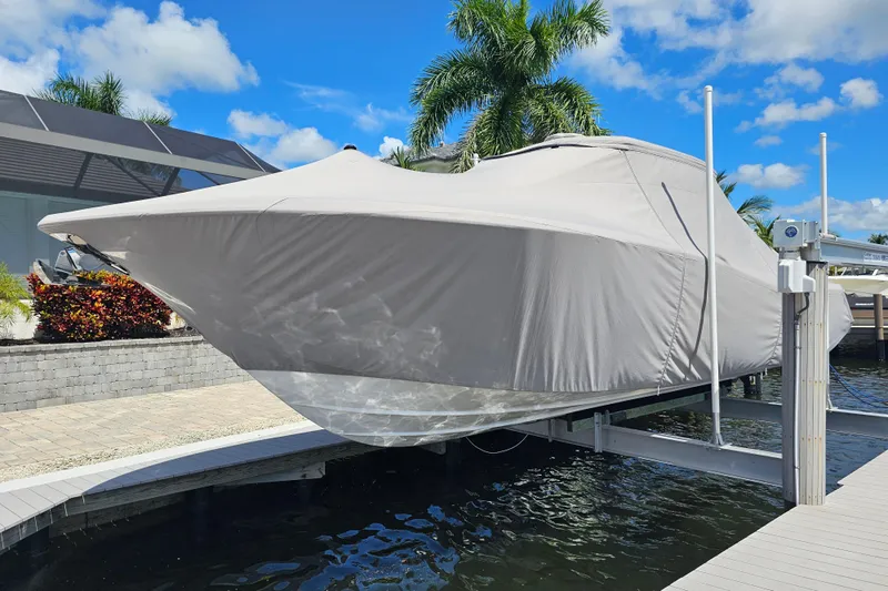 Yacht Photos Pics 2018 Tidewater 320 CC Adventure boat covered and docked, surrounded by tropical scenery.