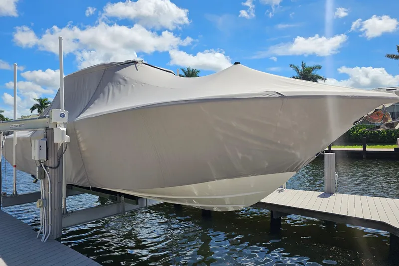  Yacht Photos Pics 2018 Tidewater 320 CC Adventure boat covered and docked by a sunny waterfront.