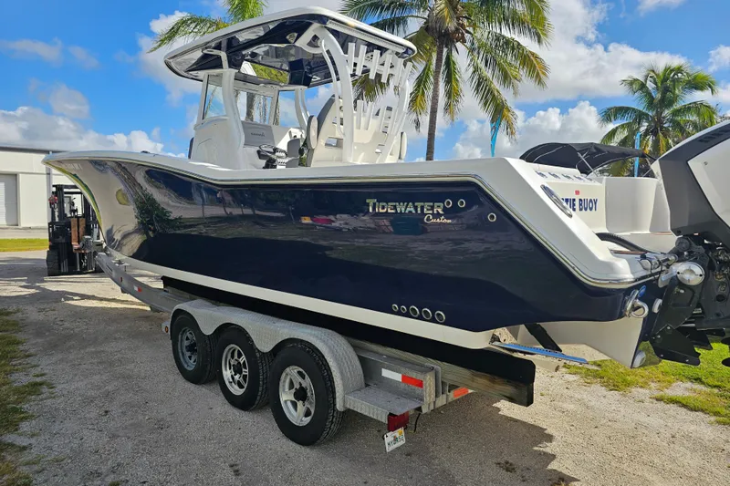  Yacht Photos Pics 2018 Tidewater 320 CC Adventure boat on trailer, parked near palm trees under a blue sky.