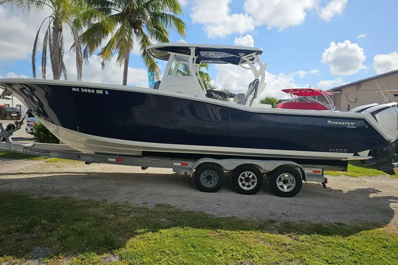  Yacht Photos Pics 2018 Tidewater 320 CC Adventure boat on trailer, parked outdoors under palm trees.