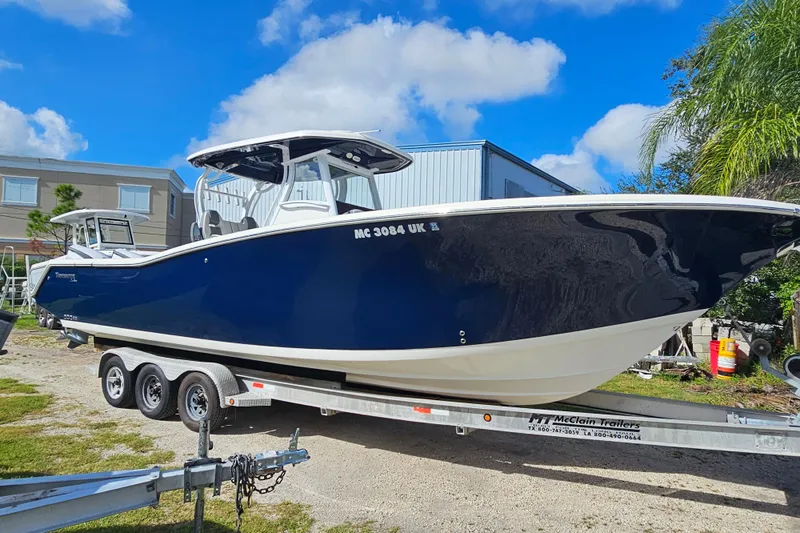  Yacht Photos Pics 2018 Tidewater 320 CC Adventure boat on trailer, parked outdoors under blue sky.