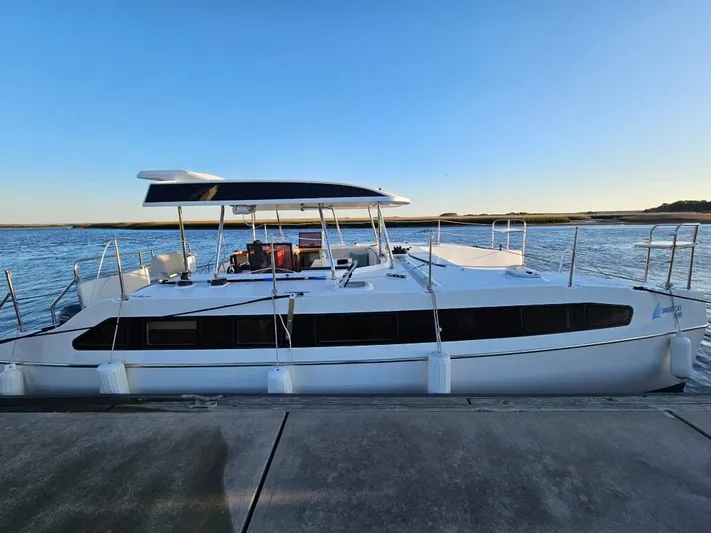  Yacht Photos Pics 2025 Smart Cat M280 Power catamaran docked by the water under a clear blue sky.