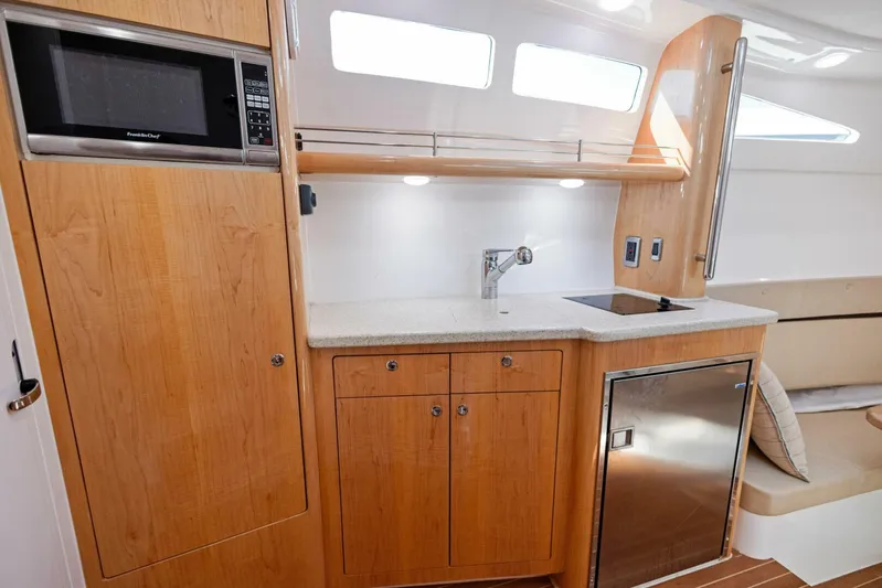  Yacht Photos Pics 2015 Intrepid 475 Panacea yacht interior with kitchenette, featuring wood cabinetry and modern appliances.