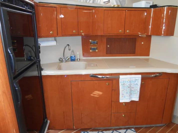 Cygnus Yacht Photos Pics Kitchen area of 2000 Sea Ray Sundancer 410 yacht with wooden cabinets and sink.