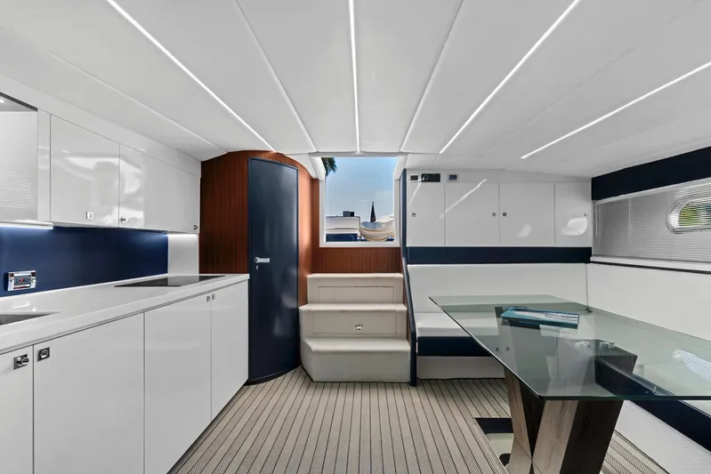 Marchese Yacht Photos Pics Modern interior of 1984 Magnum 53 yacht with sleek white cabinetry and glass dining table.