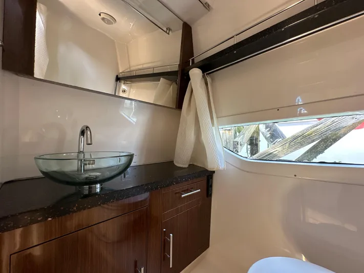Sick If Needed Yacht Photos Pics 2015 Regal 32 Express bathroom with glass sink and wooden cabinetry.