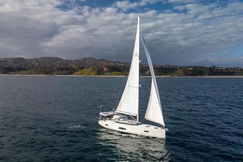Das Boot Yacht Photos Pics Sailing yacht Bavaria C57, 2020 model, cruising on open sea with scenic coastline backdrop.