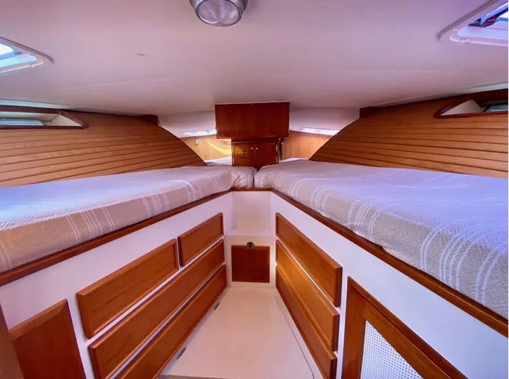 Following Sea Yacht Photos Pics Interior of a 1965 Bertram 56 boat cabin with wooden paneling and twin beds.