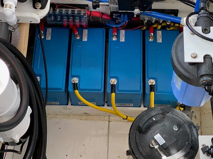 Following Sea Yacht Photos Pics Battery compartment of a 1965 Bertram 56 boat with blue batteries and yellow cables.