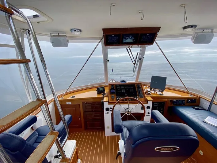 Following Sea Yacht Photos Pics Interior view of a 1965 Bertram 56 yacht cockpit with wooden accents and modern navigation equipment.